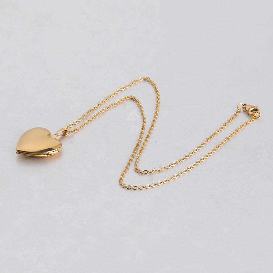 Gold heart locket necklace on white background